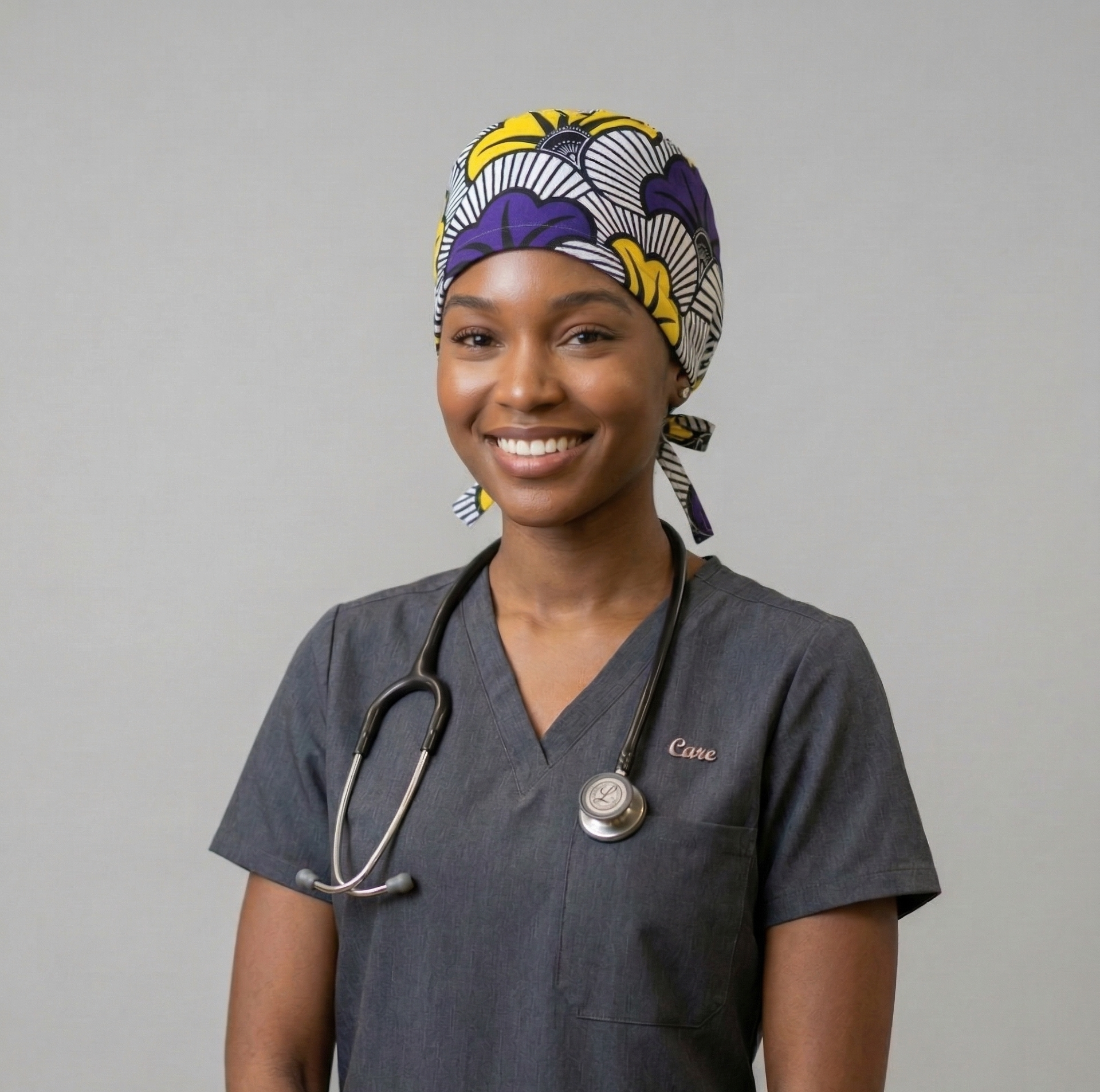 A female model in blue scrubs wearing the African Wedding Flower surgical cap against a neutral studio background.