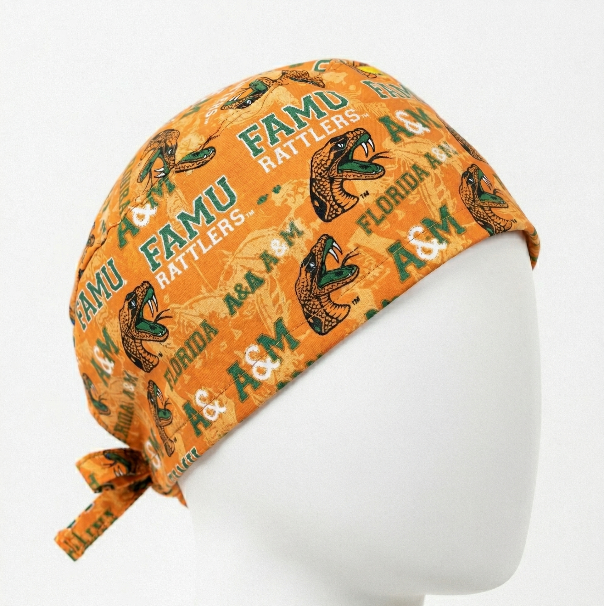 FAMU Florida A&M Rattlers Surgical Cap 1: A studio product photo of an orange surgical cap on a mannequin head. The fabric features a repeating Florida A&M University (FAMU) logo and 