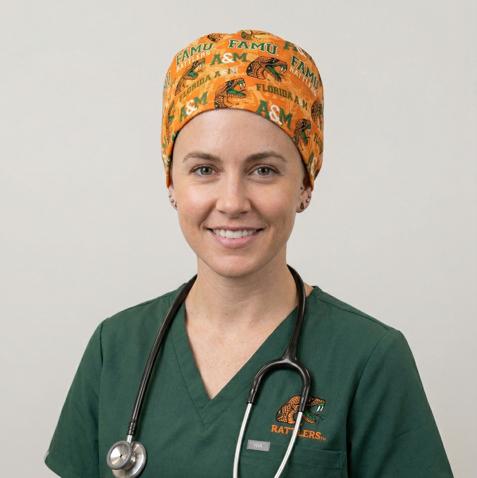 FAMU Florida A&M Rattlers Surgical Cap 2: A studio portrait of a female healthcare professional wearing dark green scrubs with a stethoscope. She is wearing the orange FAMU-themed surgical cap.