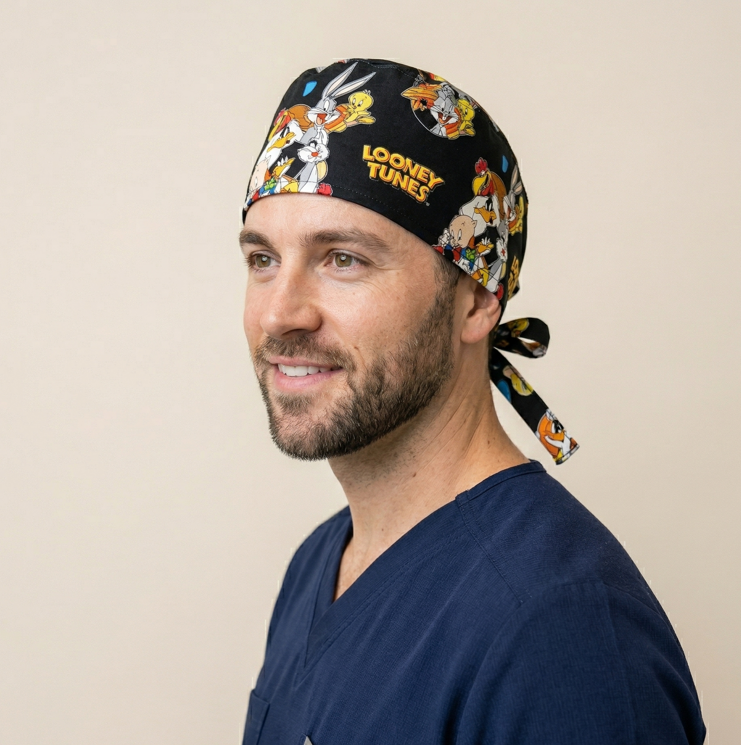 A healthcare professional in a medical office, shown in profile wearing the butterfly and hearts patterned scrub cap while looking at a laptop.