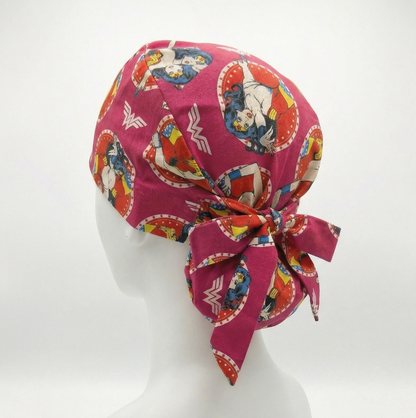 A side profile of a white mannequin head wearing a red Wonder Woman patterned scrub cap with a ribbon tie at the back.