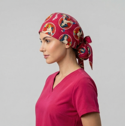 A side profile of a woman in pink scrubs wearing the Wonder Woman scrub cap against a plain grey background.